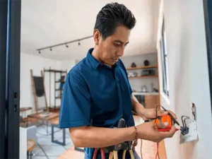 Electrician using a volt meter to test a wall outlet