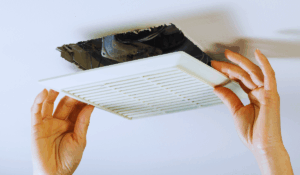 Homeowner removing bathroom fan cover