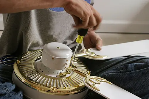 Electrician wiring and assembling a ceiling fan during installation for safe and efficient home cooling.
